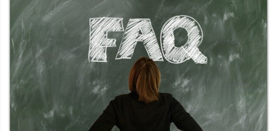 Rückansicht einer jungen Frau auf den weißen, fetten Schriftzug FAQ an einer grünen Tafel