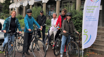 6 Teammitglieder der Freiwilligen-Agentur Leipzig stehen mit ihren Fahrrädern vor dem Büro und schauen motiviert in die Kamera.