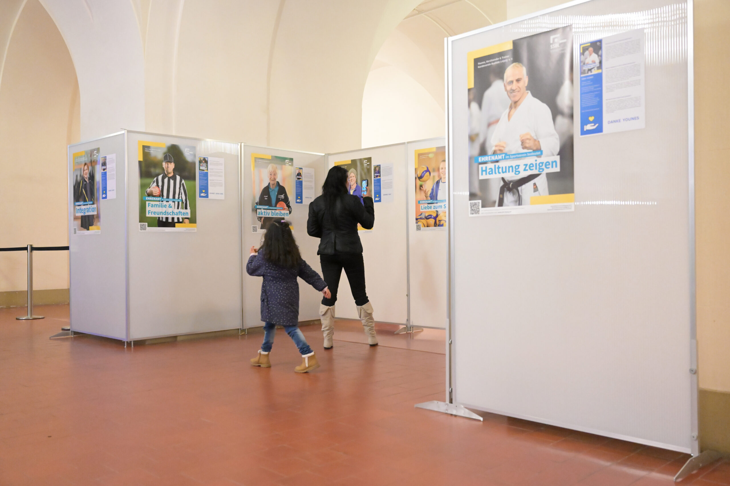 ein Kind und eine erwachsene Person betrachten Plakate der Ausstellung 