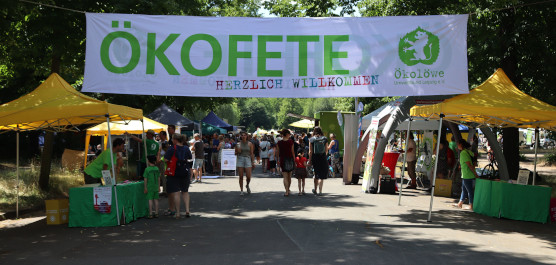Banner der Ökofete über dem Straßenfest, darunter einige Besucher*innen.