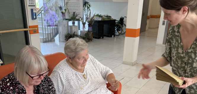 Mitarbeiterin der Freiwilligen-Agentur übergibt Briefumschläge an Bewohner*innen