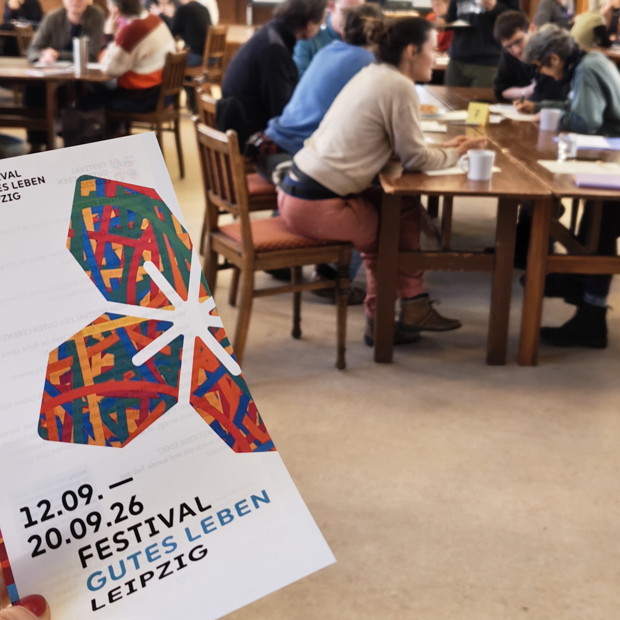 Workshop mit Leipziger*innen, im Vordergrund ein Flyer des Festivals Gutes Leben Leipzig 2026