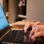 Hände tippen auf einem Laptop.