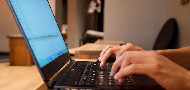 Hände tippen auf einem Laptop.